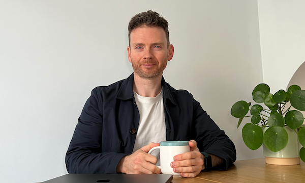 An image of Scott sitting at his desk behind a laptop